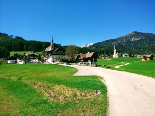 a dirt road leading to a village with a church at Pension Edelweiss Top 25 in Gosau
