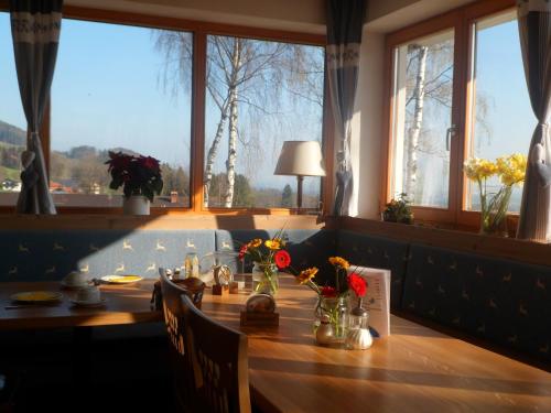 a dining room table with flowers in vases on it at Berggasthaus Kraxenberger in Brannenburg