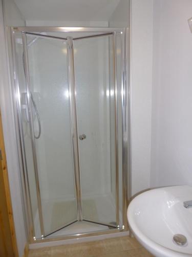 a shower with a glass door next to a sink at Goldenhill in Portree