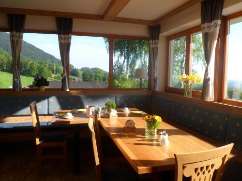 una sala da pranzo con tavolo e alcune finestre di Berggasthaus Kraxenberger a Brannenburg