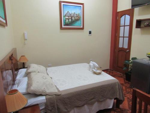 a bedroom with a bed with a picture on the wall at Alojamiento El Cardenal in Iquitos