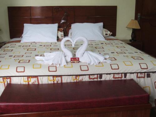 two white swans are sitting on a bed at Alojamiento El Cardenal in Iquitos