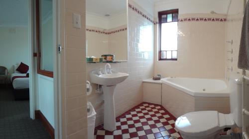 a bathroom with a sink and a tub and a toilet at Three Explorers Motel in Katoomba