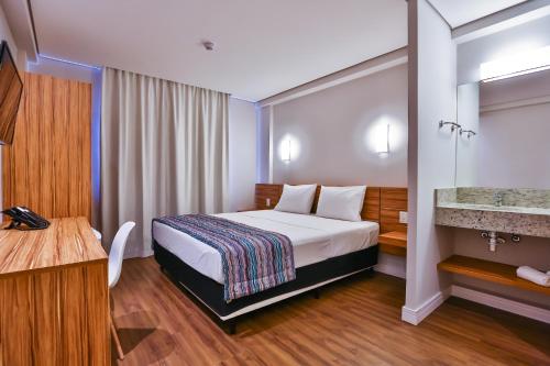 um quarto de hotel com uma cama e um lavatório em Maringá Airport Hotel em Maringá
