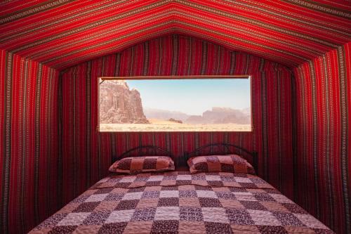 czerwony pokój z łóżkiem z oknem w obiekcie Arabian Nights w mieście Wadi Rum