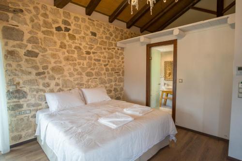 a bedroom with a large bed in a stone wall at Hotel Arhontiko Vourloka in Pramanta