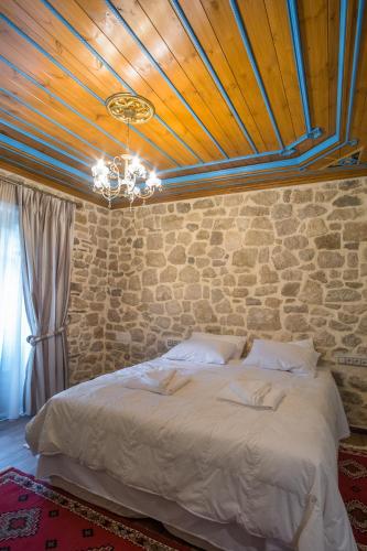 a bedroom with a large bed with a stone wall at Hotel Arhontiko Vourloka in Pramanta