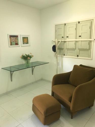 a living room with a chair and a glass table at Serrambi - 4 quartos com piscina e churrasqueira in Porto De Galinhas