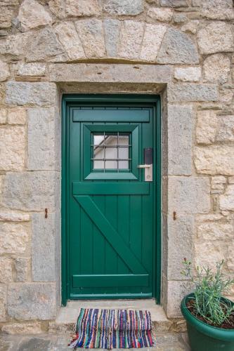 a green door in a stone building with a window at Hotel Arhontiko Vourloka in Pramanta