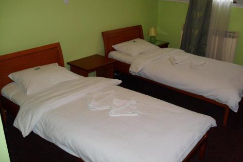two beds in a hotel room with white sheets at Hotel Vila Sunce in Stara Pazova