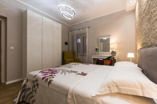 sypialnia z dużym białym łóżkiem i krzesłem w obiekcie Exclusive city center apartment with garden w Rovinj