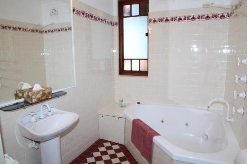 a white bathroom with a tub and a sink at Three Explorers Motel in Katoomba