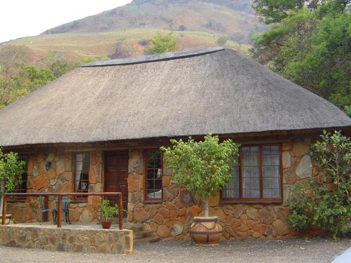 een klein stenen huis met een grasdak bij Forest Creek Lodge & Spa in Badfontein