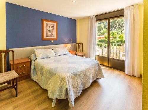 Hotel Parras Arnedillo في أرنيديلو: غرفة نوم بسرير مع جدار ازرق ونافذة