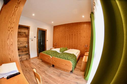 a bedroom with a bed with a green blanket at Hotel Alpenrose Wellness in Vattaro