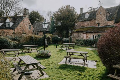 eine Gruppe von Picknicktischen in einem Hof mit Gebäuden in der Unterkunft The Falkland Arms in Chipping Norton