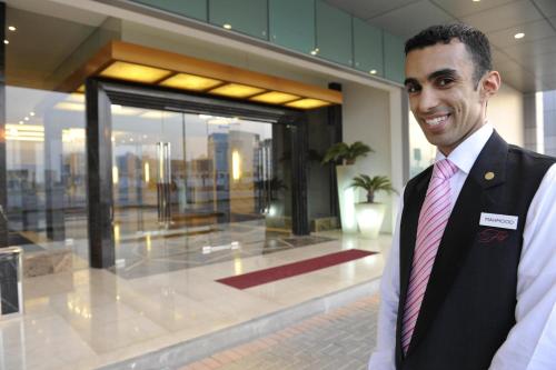 a man in a suit and tie standing in front of a building at Fraser Suites Seef Bahrain in Manama