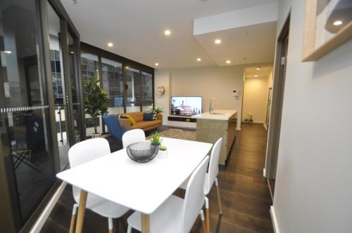 a dining room and kitchen with a white table and chairs at Orange Stay Sydney CBD in Sydney