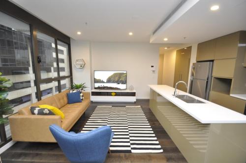 a living room with a couch and a kitchen at Orange Stay Sydney CBD in Sydney