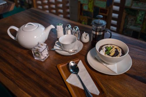 een houten tafel met een kom soep en een theepot bij Green Sala Villa in Ubud