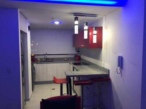 una cocina con armarios rojos y una barra con taburetes en Luxury suite in Quito, en Quito