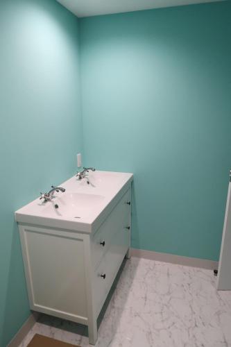 a bathroom with a white sink and a blue wall at Picnic Hostel Osaka in Osaka