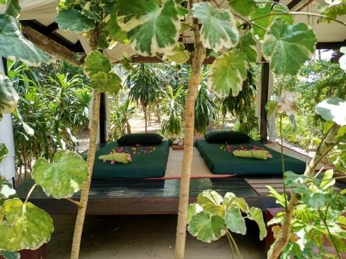 two green beds in a garden with plants at Emerald Sea Resort in Ngwesaung