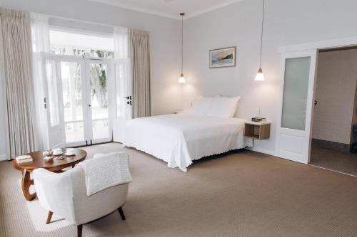 a white bedroom with a bed and a table and chairs at Winniston Lodge Luxury Accommodation in Denmark