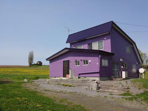 a purple house sitting on top of a field at Cottage CLOVER in Biei