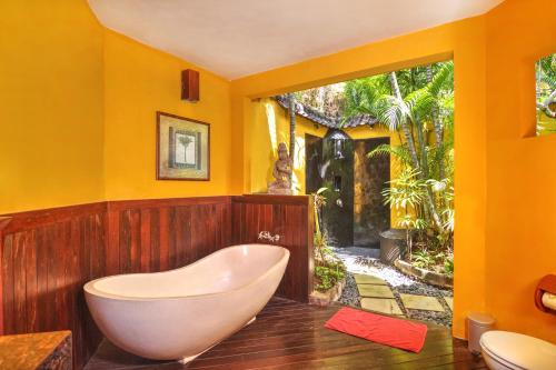 a bath tub in a bathroom with yellow walls at Villa Plawa Asri in Seminyak