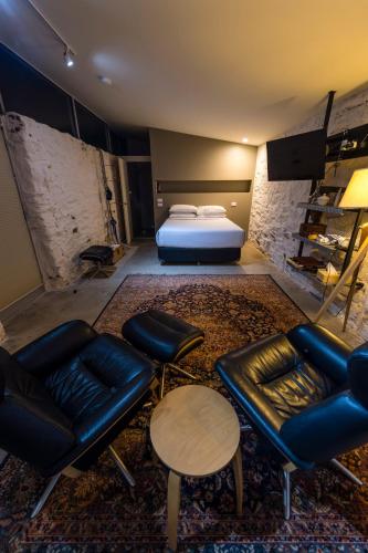 a bedroom with a bed and a couch and chairs at Dairyman's Cottage in Lyndoch