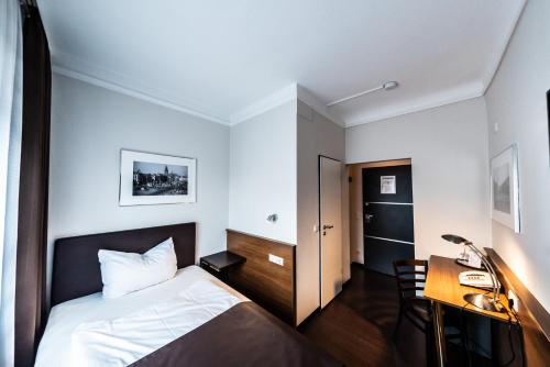 a small bedroom with a bed and a desk at Mauritius Komfort Hotel in der Altstadt in Cologne