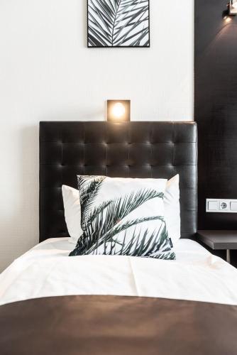 a bedroom with a bed with a black headboard and pillows at Mauritius Komfort Hotel in der Altstadt in Cologne