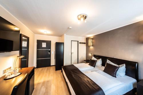 una camera d'albergo con un grande letto e una scrivania di Mauritius Komfort Hotel in der Altstadt a Colonia