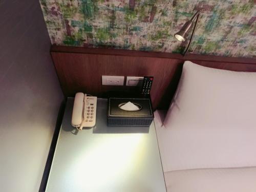 a bed with a phone and a keyboard and mouse at Ueno Hirokoji 428 in Taipei