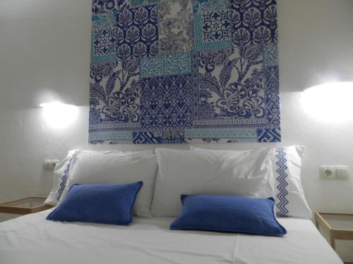 Una cama con dos almohadas azules encima. en Stylish Studios, en Moírai