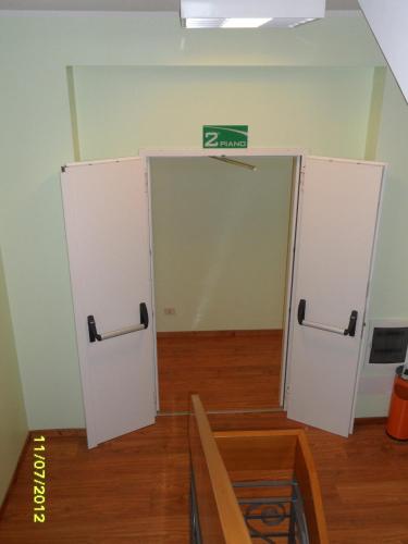 an empty room with two white doors with a green sign at Hotel Prati in Castrocaro Terme