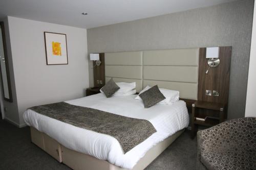 una habitación de hotel con una cama grande y una silla en The Hind Hotel en Wellingborough