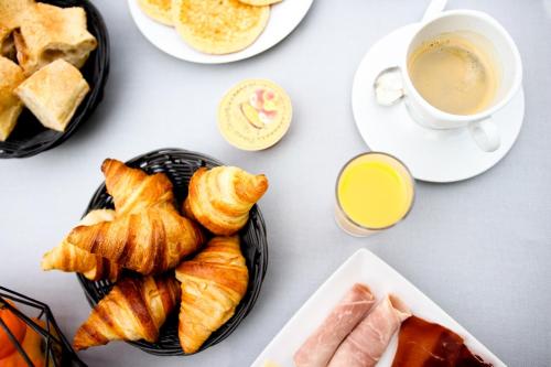 a table with plates of pastries and a cup of coffee at Hotel La Tuiliere in Carry-le-Rouet