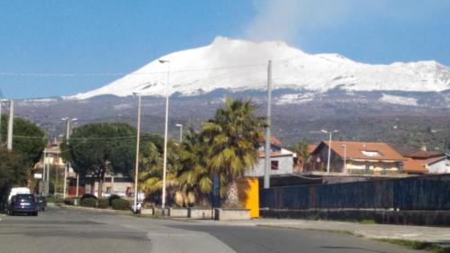 a snow covered mountain in the background of a street at Oriente Dell'Etna in Belpasso