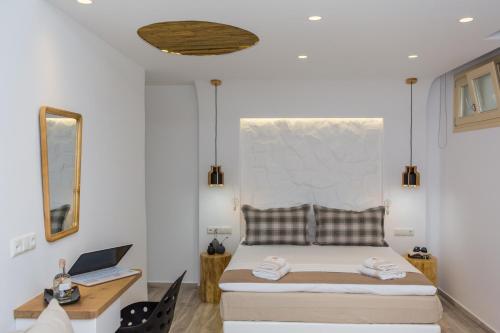 a bedroom with a bed and a desk with a laptop at Korali Hotel in Naxos Chora