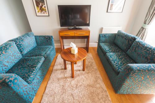 a living room with two blue couches and a table at Raasay House Hotel in Raasay