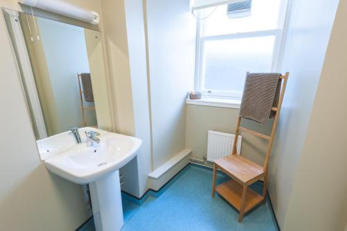 a bathroom with a sink and a chair next to a window at Raasay House Hotel in Raasay