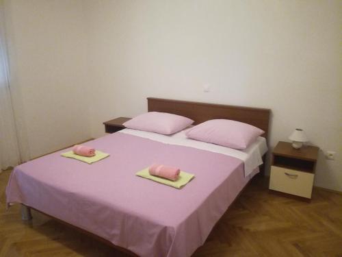a bed with pink pillows and pink towels on it at Apartman Lucija in Zadar