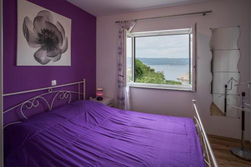 a purple bedroom with a bed and a window at Apartments Stasic in Vrbnik