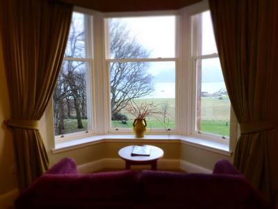 a living room with a couch and a large window at Raasay House Hotel in Raasay