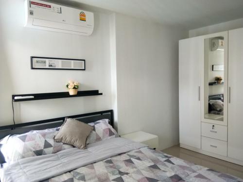 Un dormitorio con una cama y una pared blanca. en GrandBeach Condo by malai, en Rayong