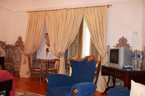 a living room with blue chairs and a tv at Casa D. Diogo in Arraiolos