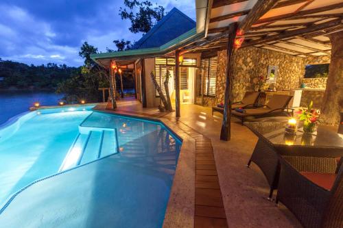 a swimming pool with a table and chairs next to a house at Savasi Island Resort in Savusavu