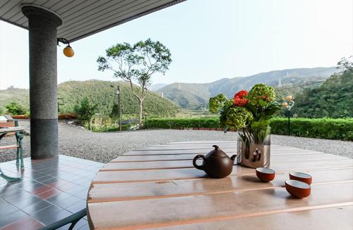 a wooden table with a vase and flowers on it at Song Lin Homestay in Dongshan